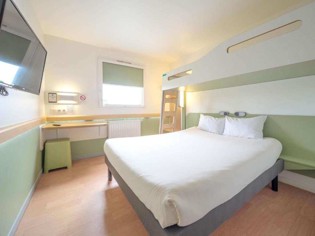 a bedroom with a large white bed and a television at Ibis Budget Sarrebourg Buhl in Sarrebourg