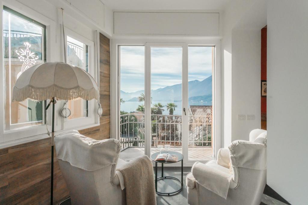 a living room with two chairs and a table and a large window at Villa Casa Pini by Rent All Como in Bellagio
