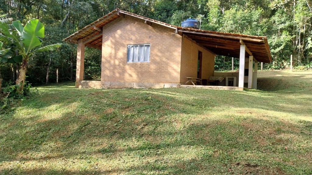 a small house on a grassy field in front at Chácara chalé in Juquitiba