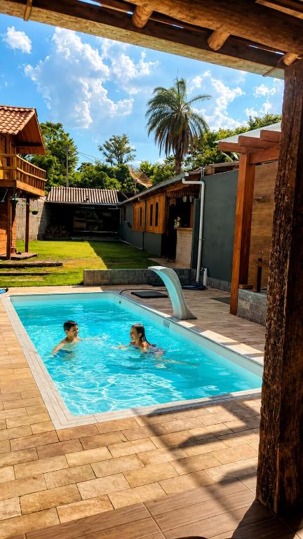 two people are swimming in a swimming pool at Sitio em Capim Branco in Capim Branco