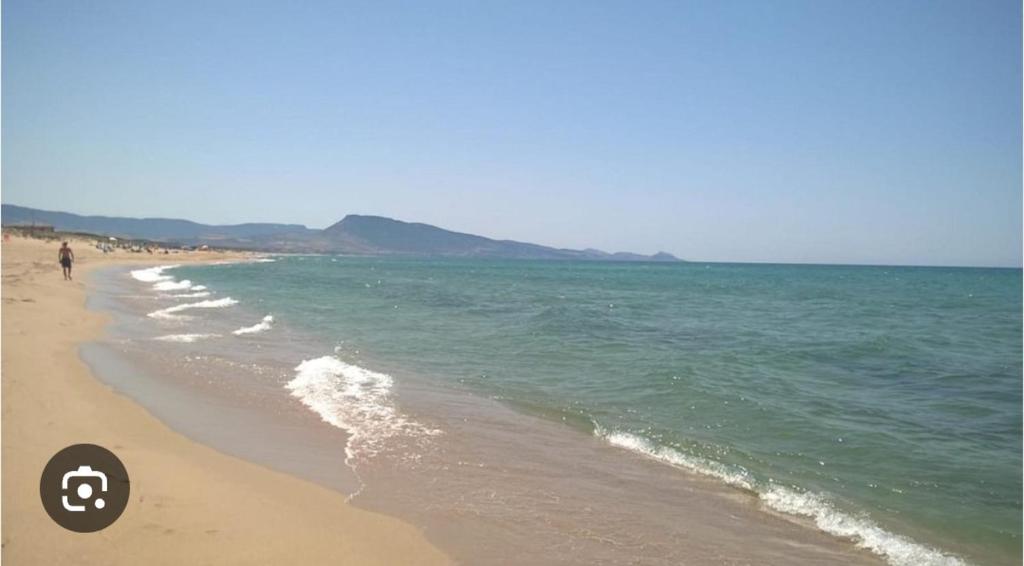 a person walking on a beach near the ocean at Sa Mùrtya casa vacanza in Viddalba