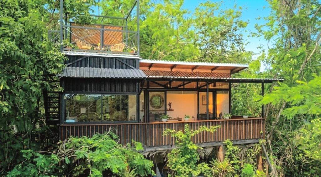 a house in the forest with a balcony at Cocolhu Treehouse & Ocean View in Tamarindo