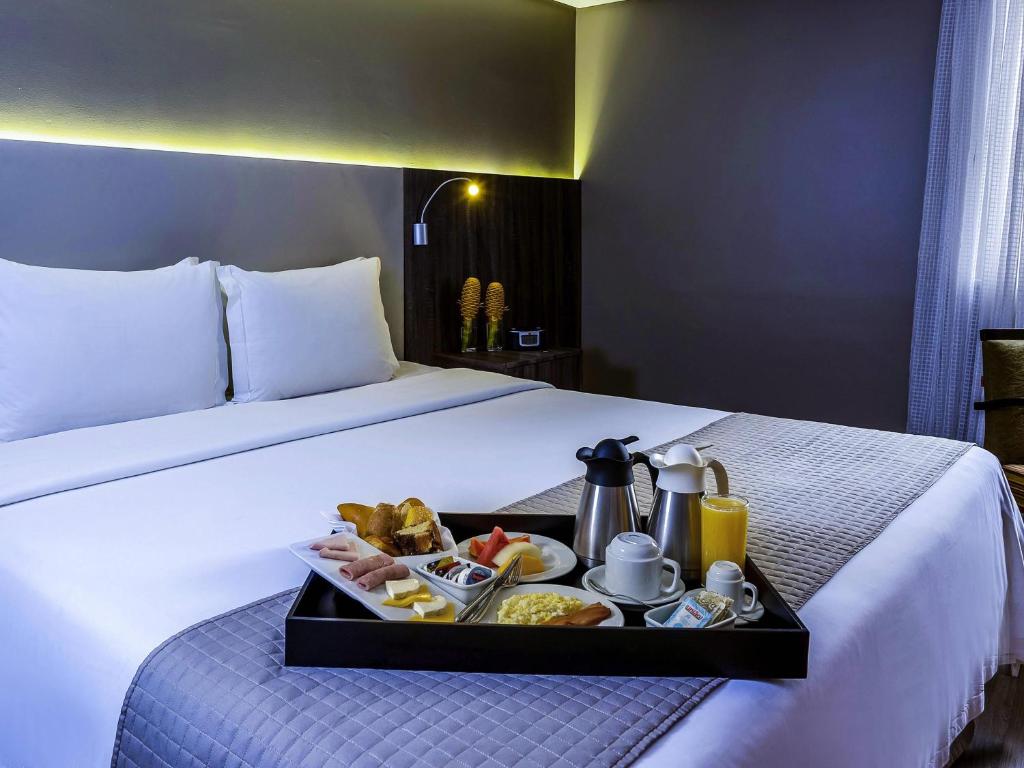 a tray of food on a bed in a hotel room at Grand Mercure Belem do Para in Belém