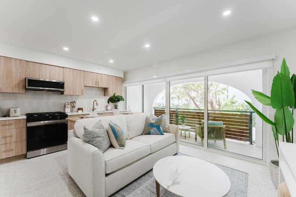 a living room with a white couch and a kitchen at Casa Luz - Sunlit Boca Pool Retreat in Boca Raton