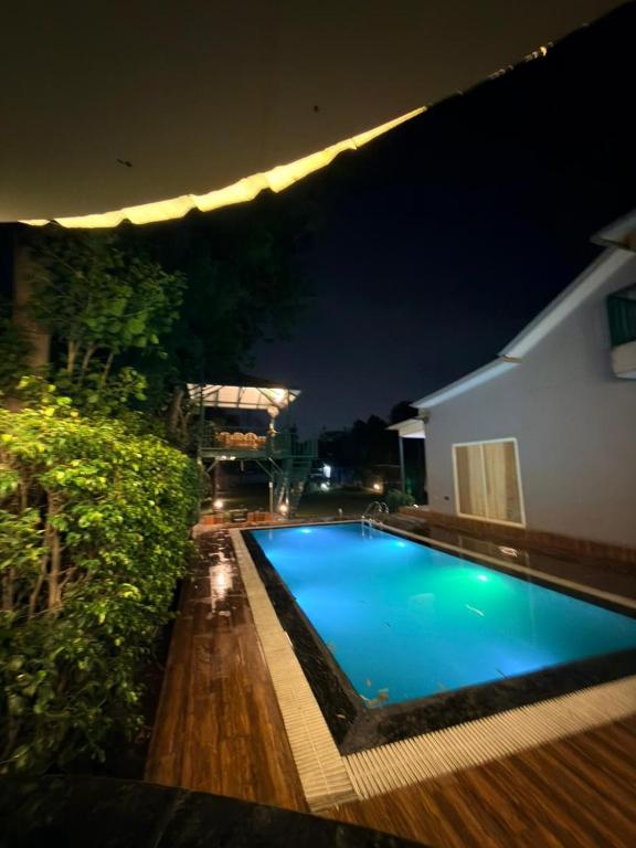 a swimming pool in front of a building at night at Luxurious Farm in Greater Noida