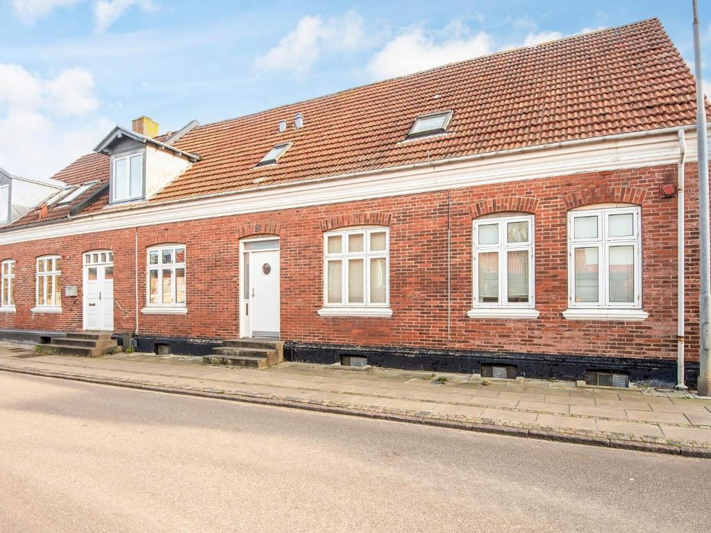 a red brick building with white doors on a street at Charming Retreat in Ringkobing in Ringkøbing