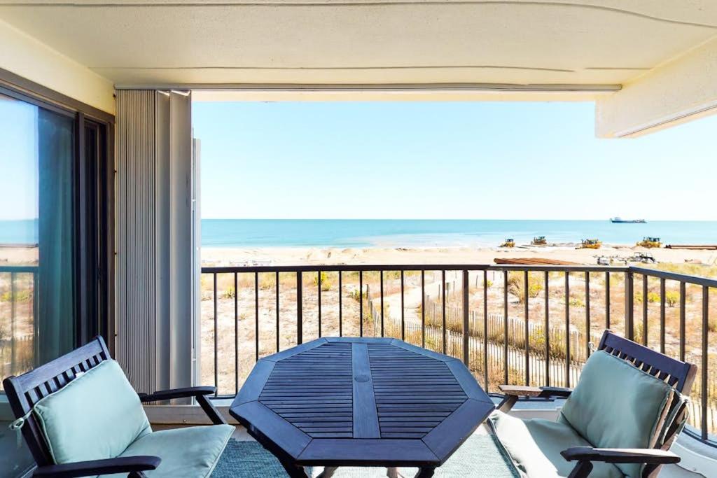 a balcony with a table and chairs and the beach at Waikiki 102 in Ocean City