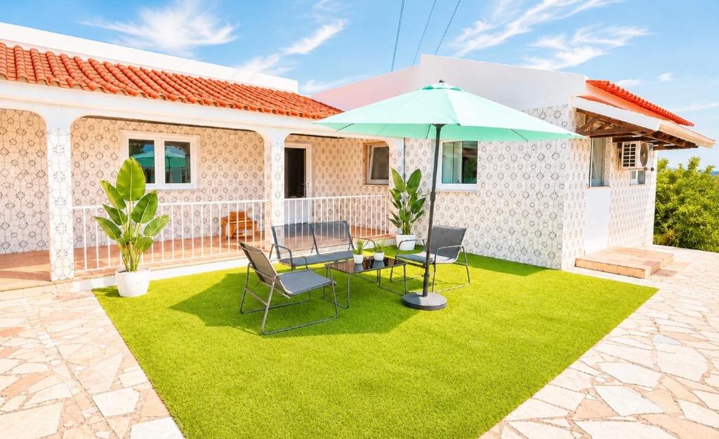 eine Terrasse mit Tisch, Stühlen und Sonnenschirm in der Unterkunft PineHills in Torres Vedras