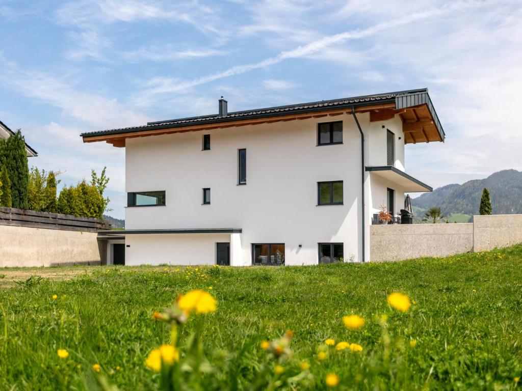 a white house on a hill with a green field at Mosers Apartment in Reith im Alpbachtal