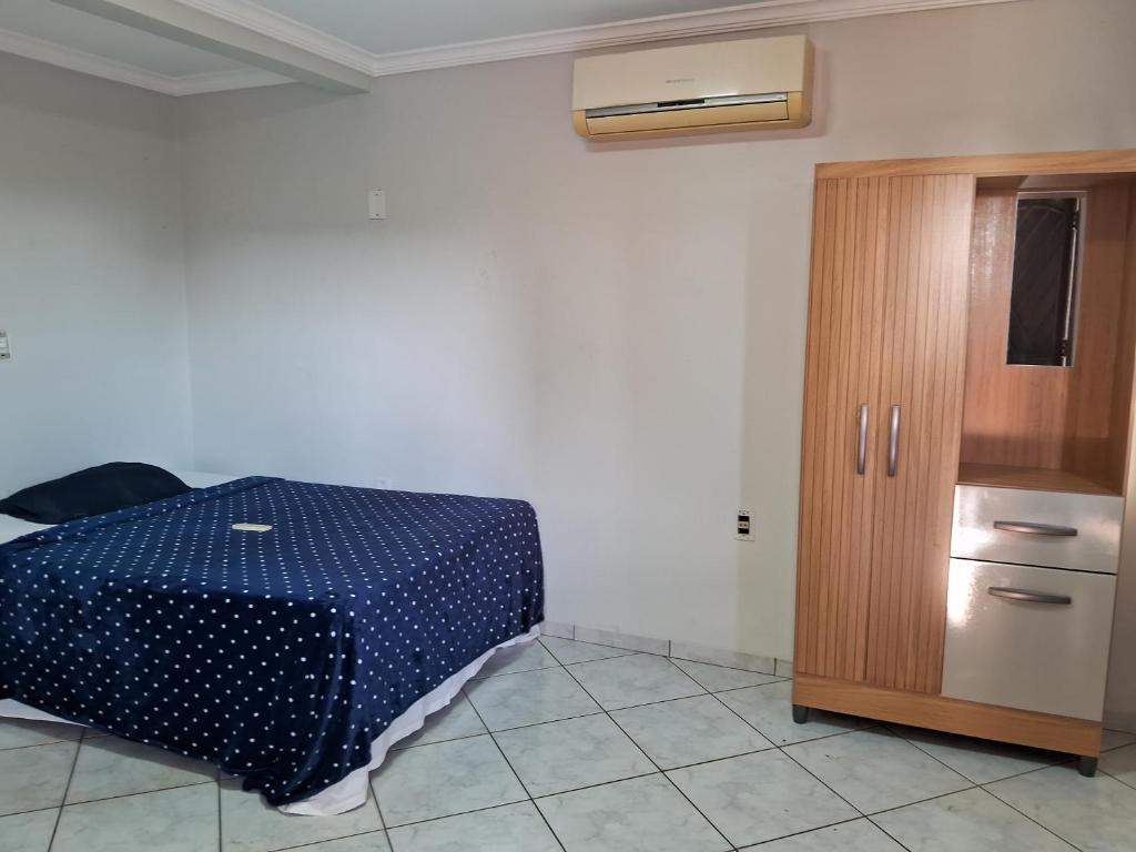a bedroom with a bed and a wooden cabinet at Pousada Exclusiva in Rondonópolis
