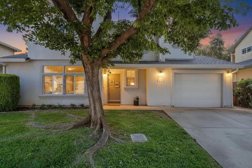 a white house with a tree in the yard at Modern 3BR Davis Retreat in Davis