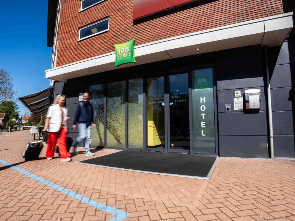 two people walking in front of a store at ibis Styles Haarlem City in Haarlem