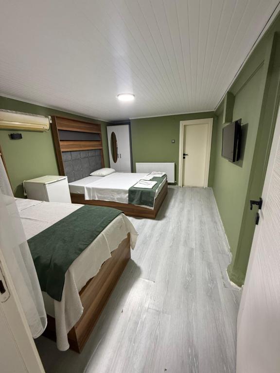 two beds in a room with green walls and wooden floors at Başkent otel in Mudanya