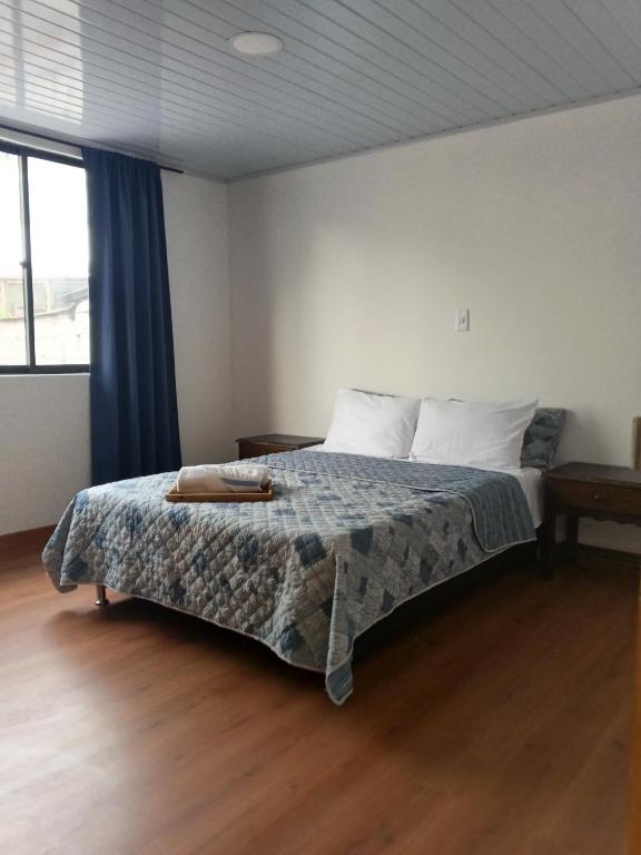 a bedroom with a bed with a blanket and a window at Arboleda in Manizales