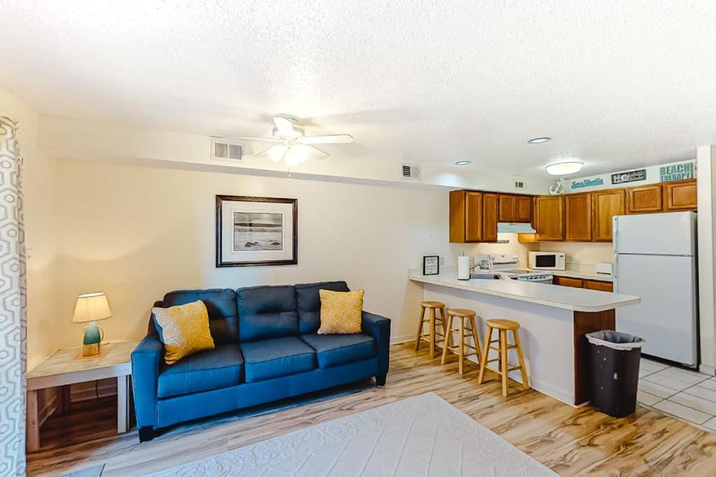 a living room with a blue couch and a kitchen at Jamaica Bay 105A in Ocean City