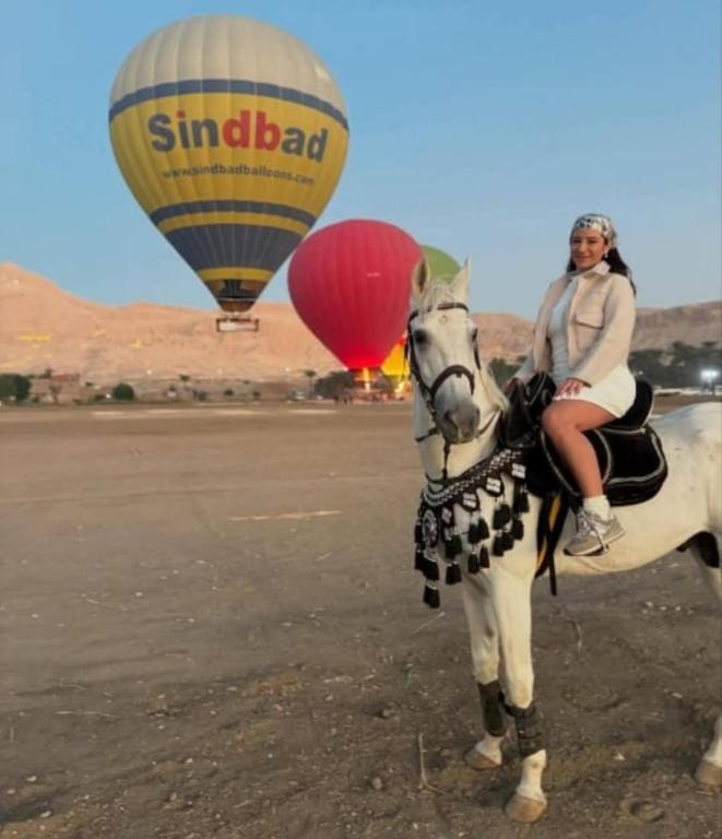 a woman riding a horse with a hot air balloon at Flower House in Al Aqālitah