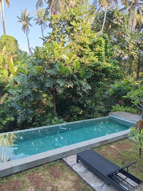 a swimming pool in a garden with trees at Jagadhita sekembang ubud in Ubud