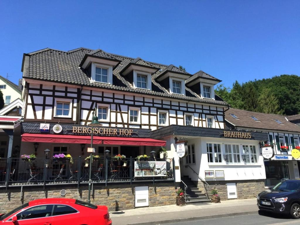 ein rotes Auto, das vor einem Gebäude parkt in der Unterkunft Bergischer Hof in Overath