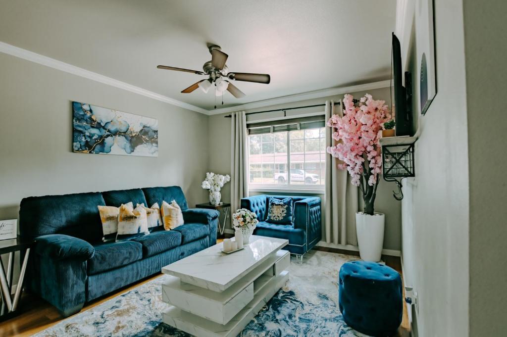a living room with a blue couch and a table at The Homestead Luxury Cozy 2BR Apartment in Nacogdoches Near SFA University and Downtown Pet Friendly Business Ready Extended Stays Welcome with Self Check In High Speed WiFi Full Kitchen In Unit Laundry Private Parking and Quiet Comfort in Nacogdoches