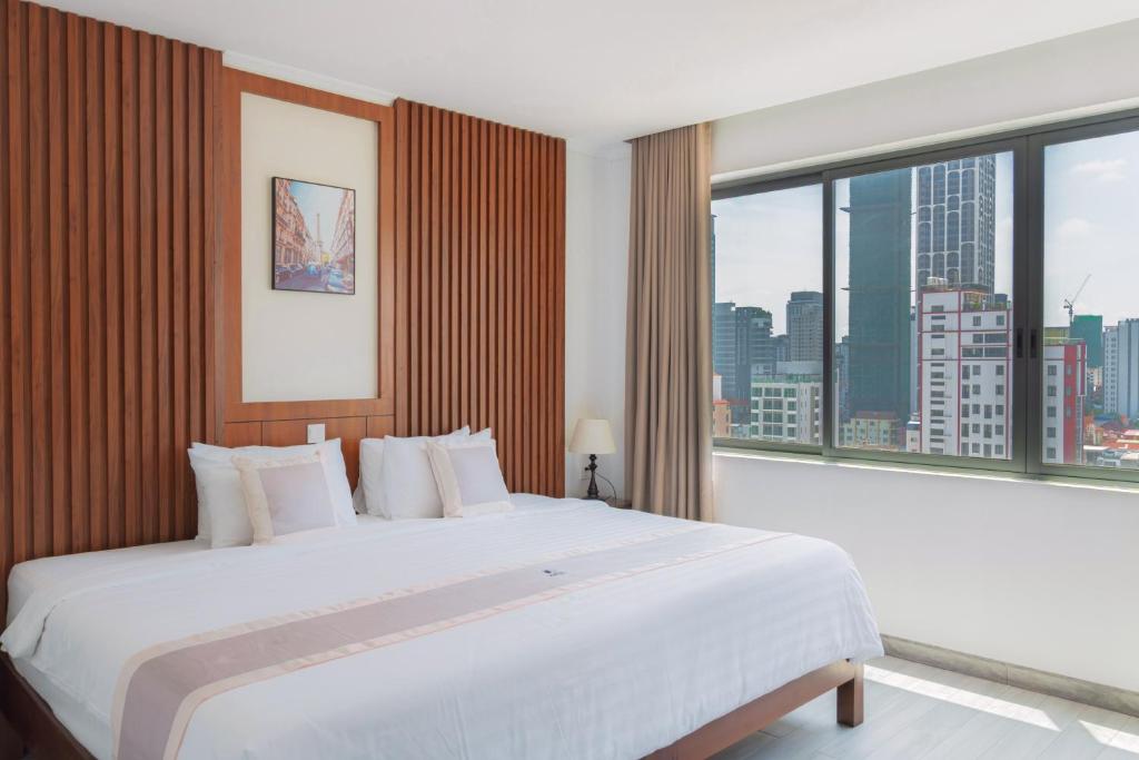 a bedroom with a large white bed and large windows at The ONRA Hotel in Phnom Penh