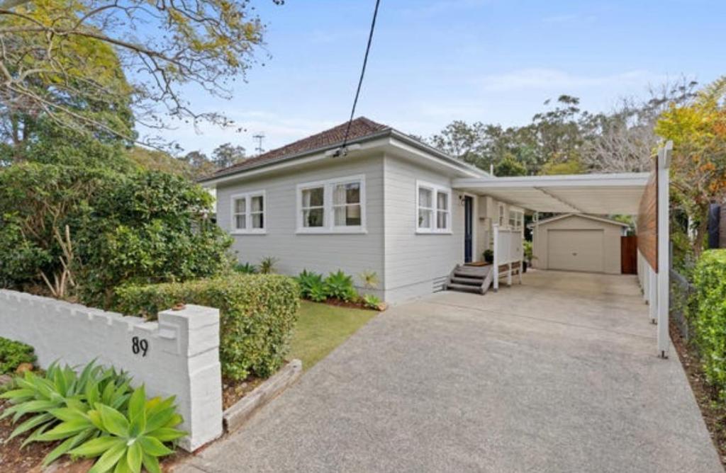 a white house with a driveway in front of it at The Seaside Haven Umina in Umina