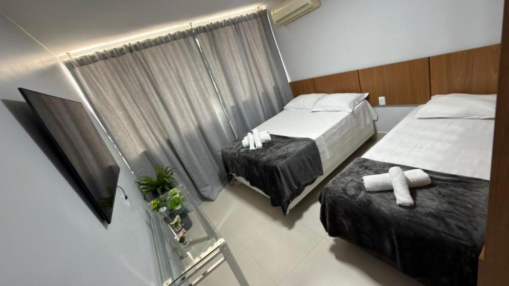 a hotel room with two beds and a window at Loft centro de Goiânia 1108 in Goiânia