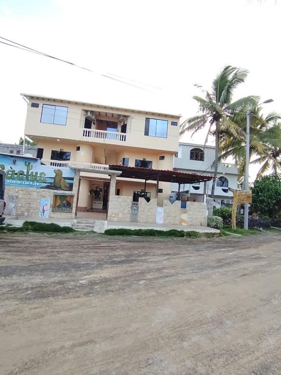 a large building with a palm tree in front of it at Hospedaje Cactus Experience in Puerto Villamil