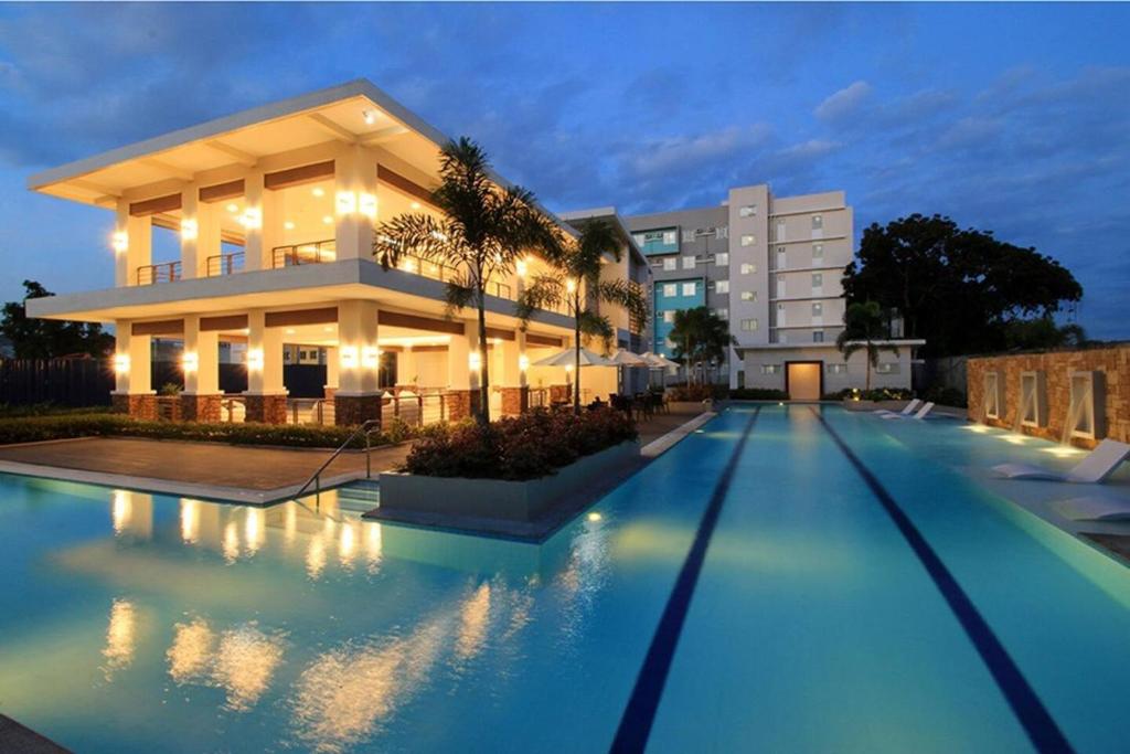 a villa with a swimming pool in front of a building at Cozy 2BR Retreat at 8 Spatial Davao in Davao City