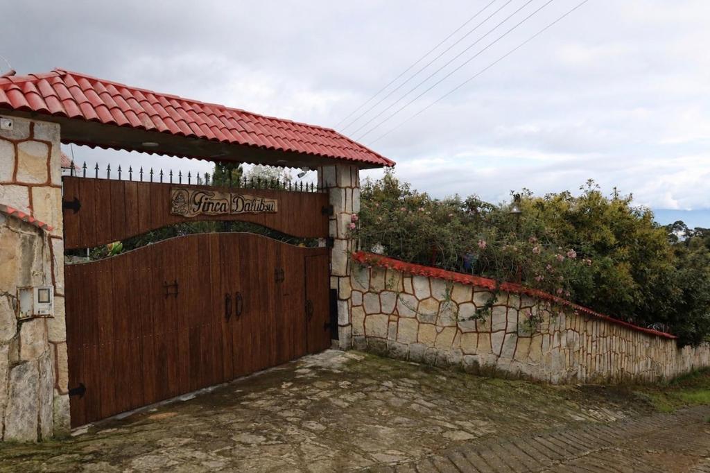 a wooden gate to a house with a stone wall at Finca eventos Dalubsu in Silvania