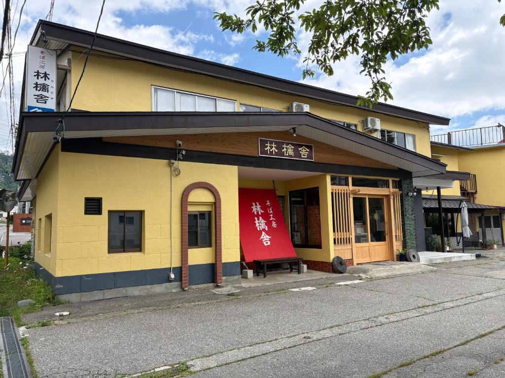 a yellow building with a red sign on it at Ringoya in Hakuba