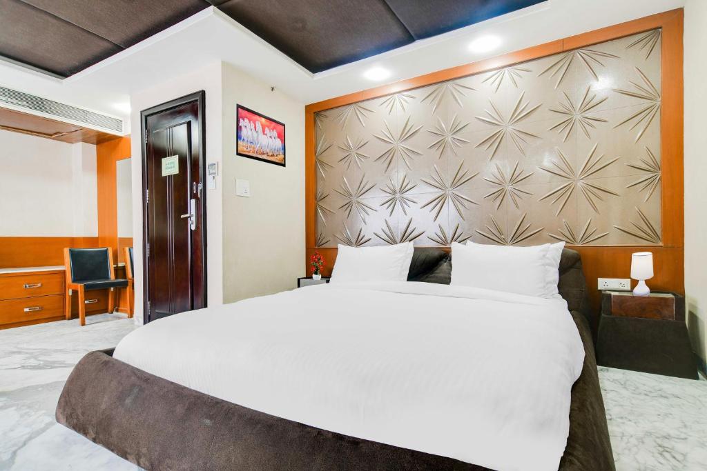 a bedroom with a large white bed and a wall at Palette by CheckIn Chappan Market Indore Formerly Sapphire Star in Indore