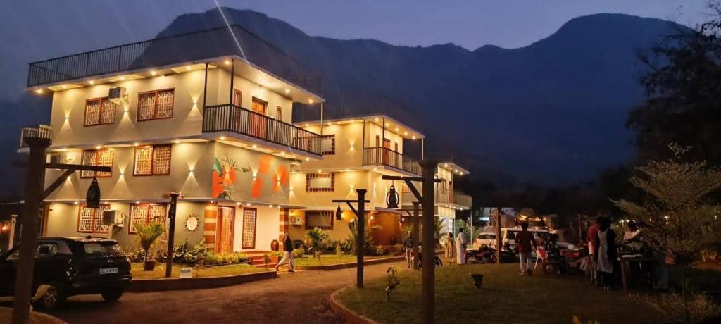 a large white building with people standing outside of it at Mountain Meadows Resort in Kollengode