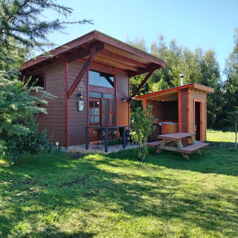 a small cabin with a picnic table in the grass at cabañas roccajoma in Salto del Laja