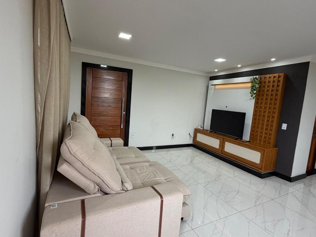 a living room with a couch and a television at Estrela-do-mar in Serra
