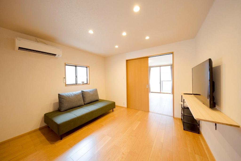 a living room with a green couch and a flat screen tv at SaiKa 隠れ家 in Saikamachi