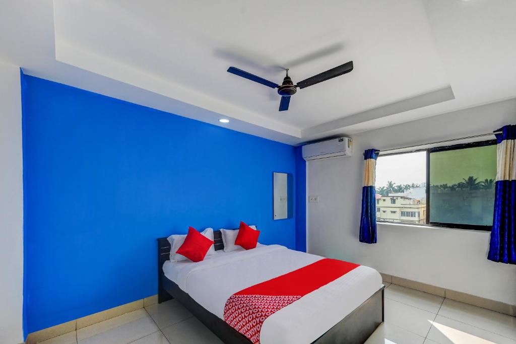 a blue bedroom with a bed with red pillows at Hotel O Utrishree in Khandagiri