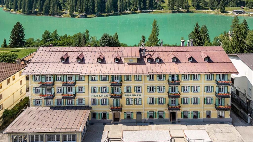 an aerial view of a building with a lake in the background at Hotel Auronzo Dolomites, Affiliated by Melia in Auronzo di Cadore