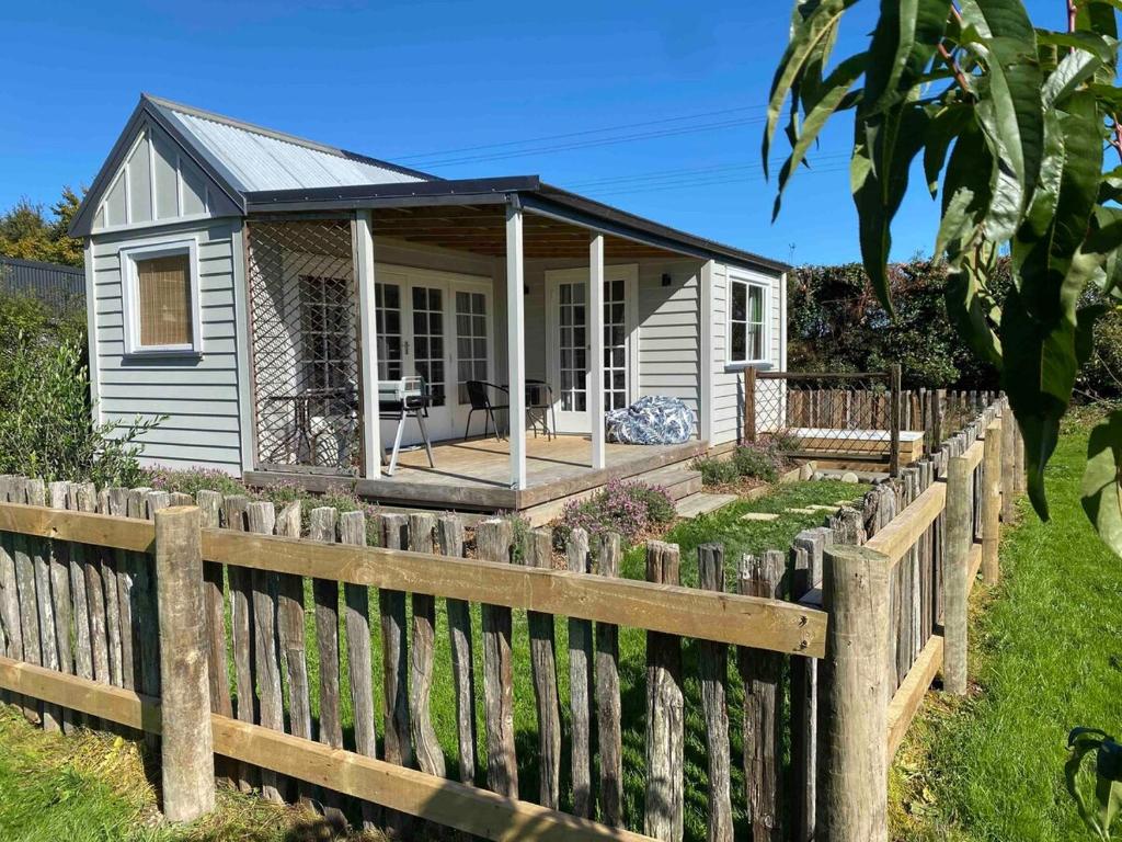 a small house behind a wooden fence at Kingfisher Cottage in Masterton