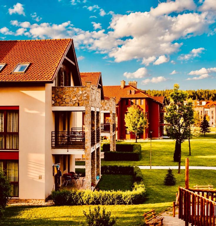 a house with a green yard and buildings at Birdland Apartman in Bük