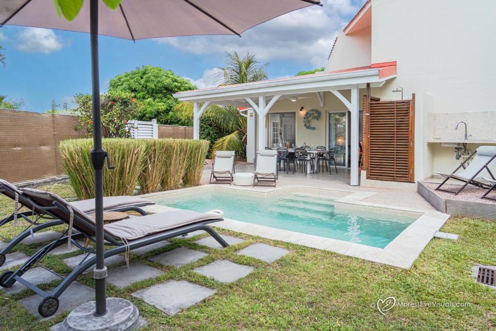 a house with a swimming pool and an umbrella at Villa Karmen in Le Diamant