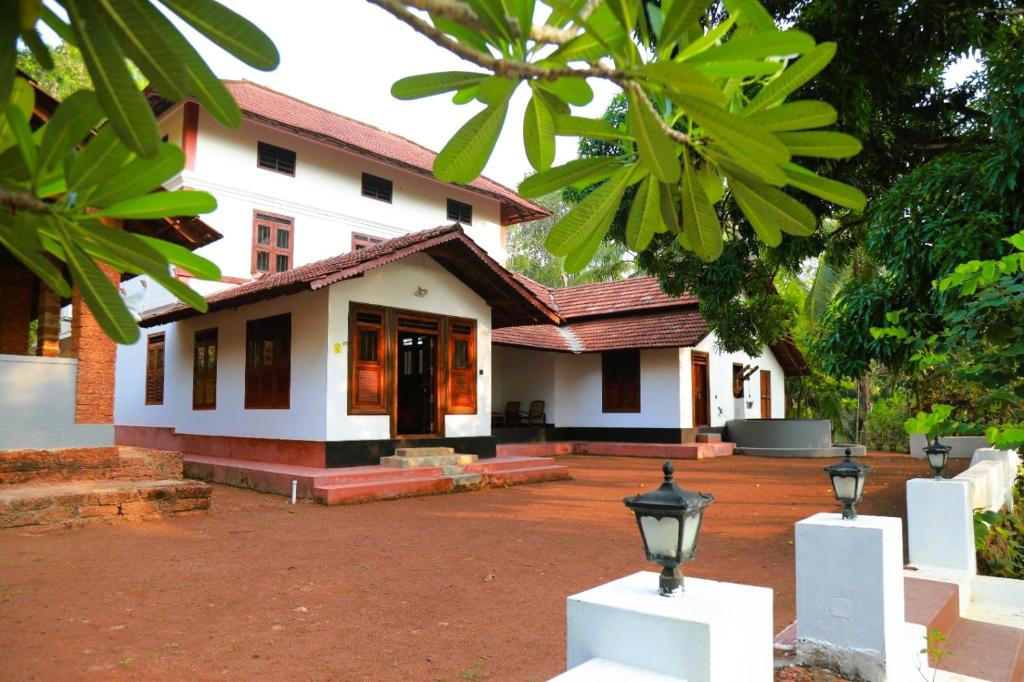 a white house with a street light in front of it at Vilayara Heritage Retreat -Kozhikode in Kunnamangalam