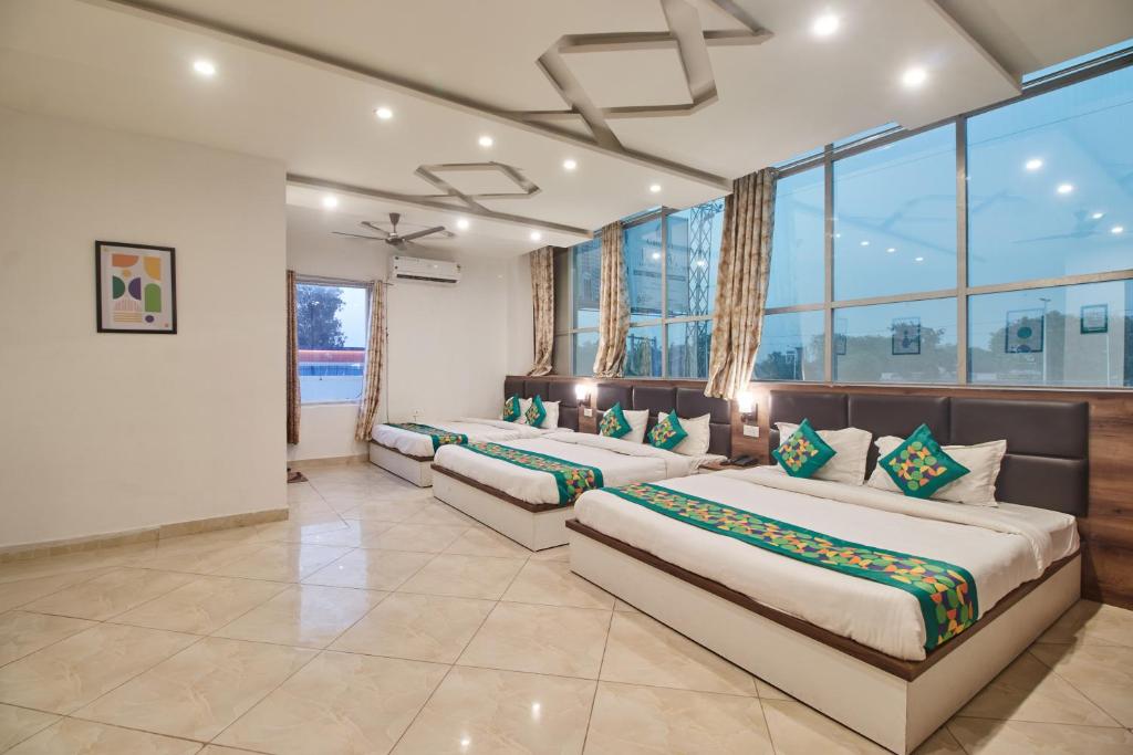two beds in a room with large windows at Treebo Chanakya Palm in Chhatikara