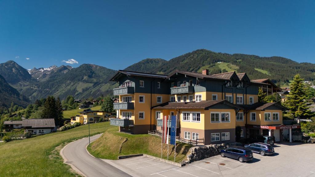 a large building on a hill with mountains in the background at Apparthotel Bliem in Schladming