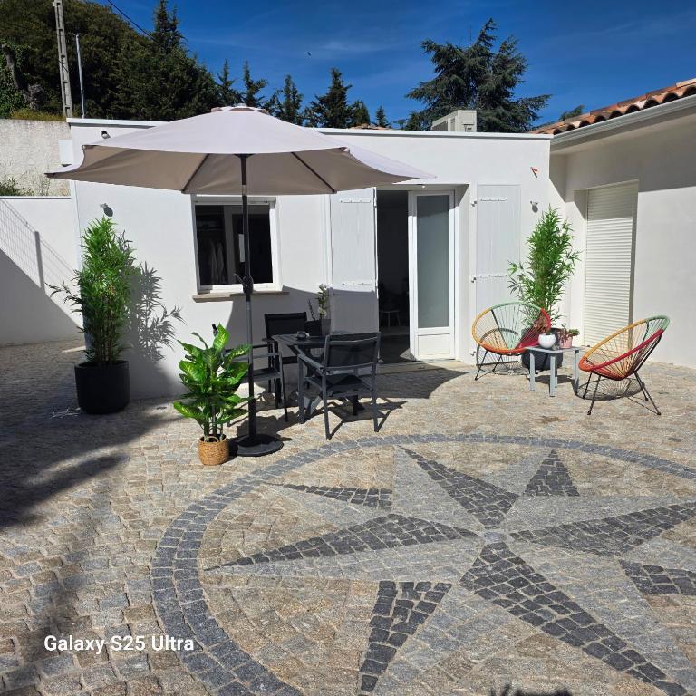 eine Terrasse mit Tisch und Sonnenschirm in der Unterkunft Chez philo in Alata