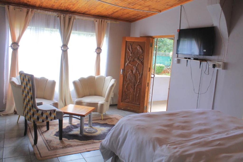 a bedroom with a bed and a television and chairs at One love suites in Mokopane