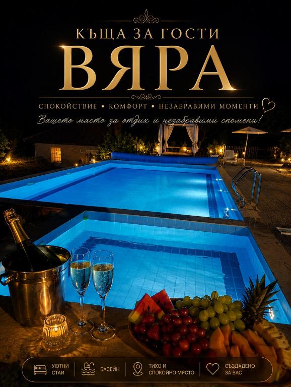 a swimming pool with wine glasses and a tray of fruit at "Бадевски рай" Къща за гости ВЯРА in Elena