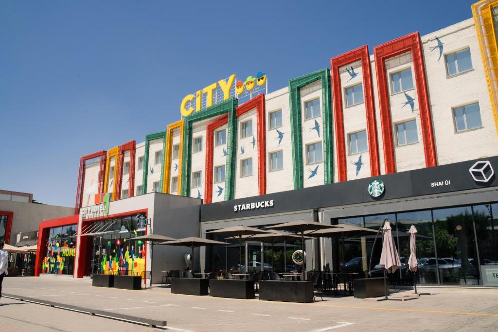 a store front of a building with tables and umbrellas at City Hotel Shymkent in Shymkent