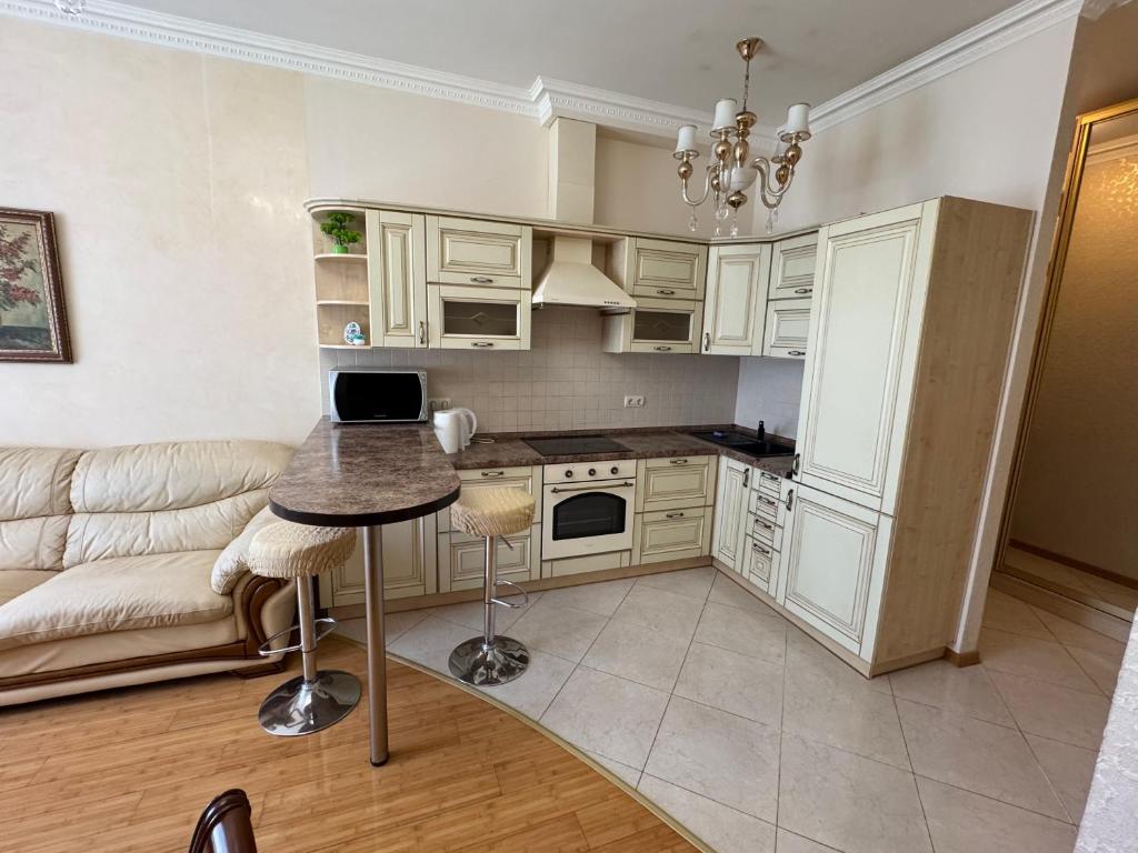 a kitchen with white cabinets and a table and a couch at Аркадия, Генуэзская in Odesa
