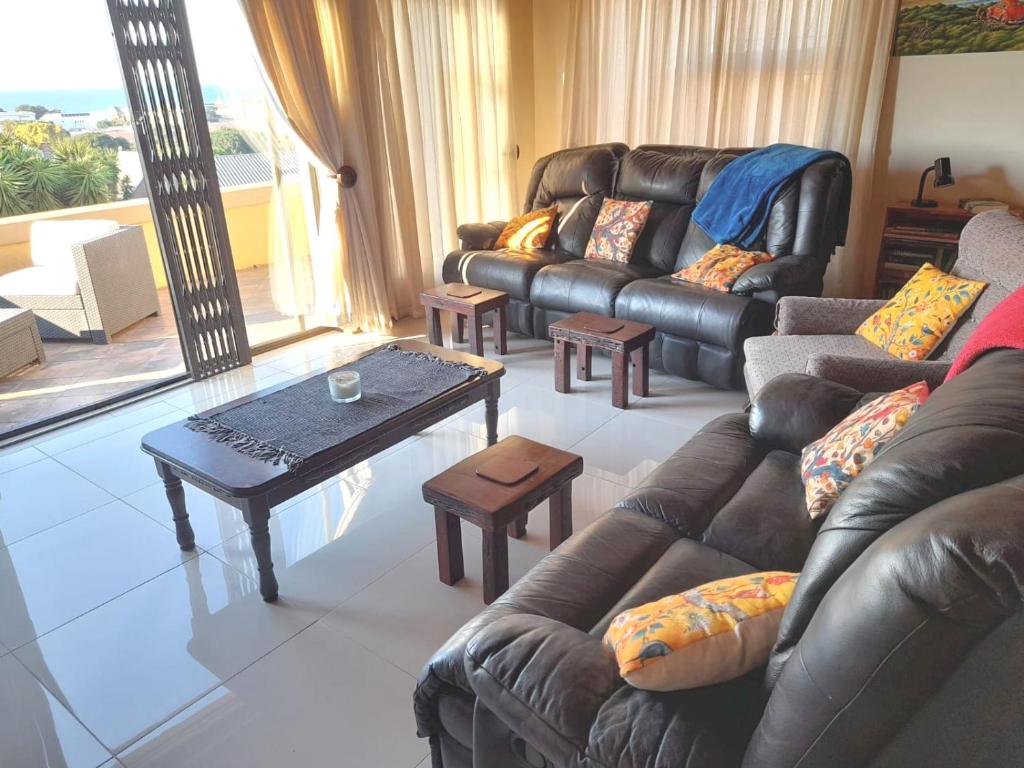 a living room with a leather couch and a coffee table at 17 Villa Leadwood in Jeffreys Bay
