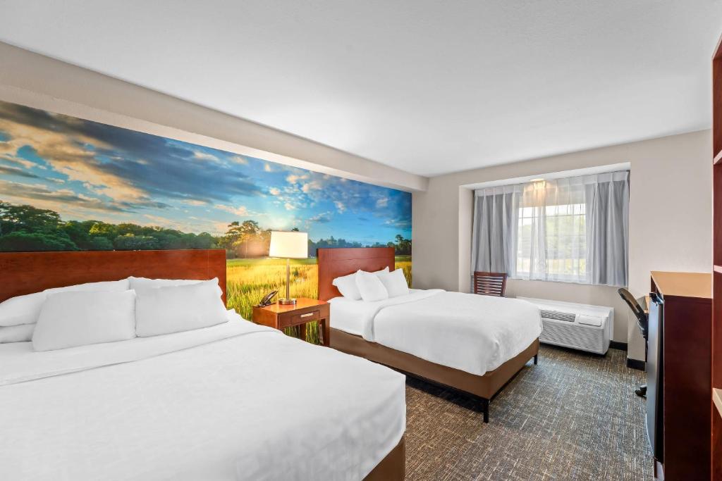 a hotel room with two beds and a painting at Clarion Pointe Starkville near University in Starkville